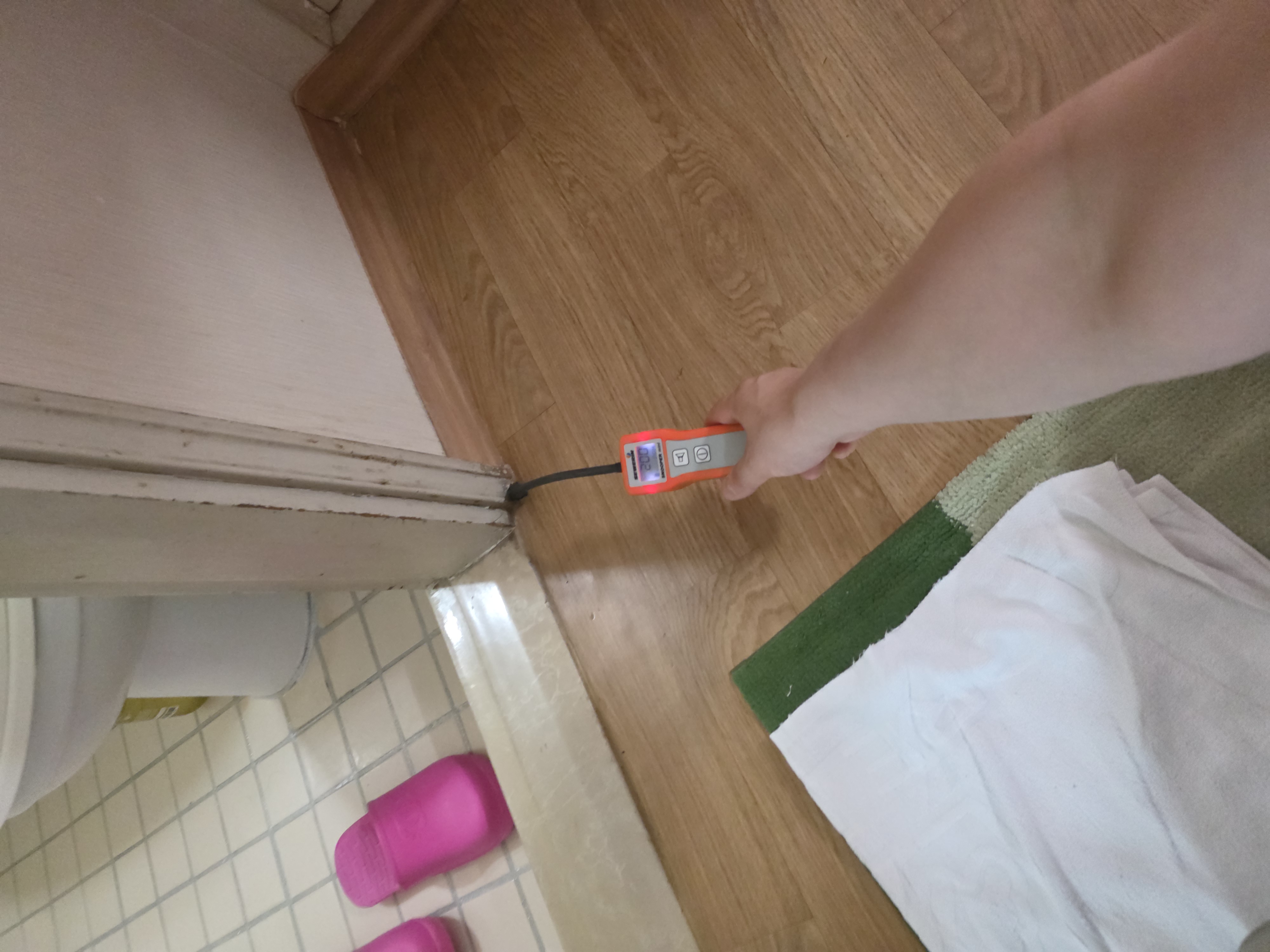 문틀과 바닥이 만나는 자리를 탐지 장비로 확인하는 모습